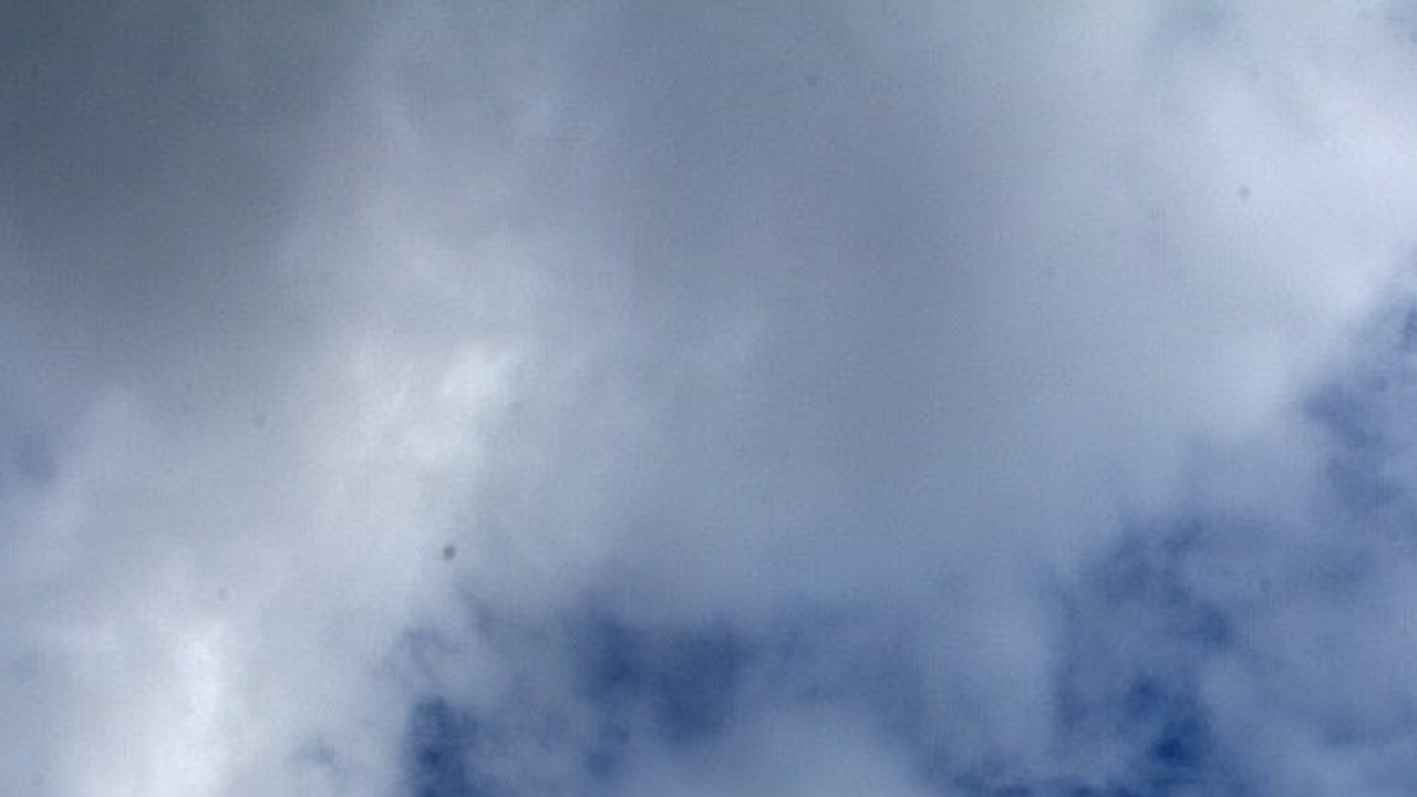 Cloudy sky with a mix of white and gray clouds, partially covering a blue sky background.