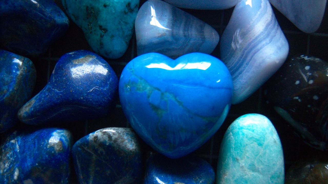 A collection of various polished blue stones, including a heart-shaped one, displayed closely together.